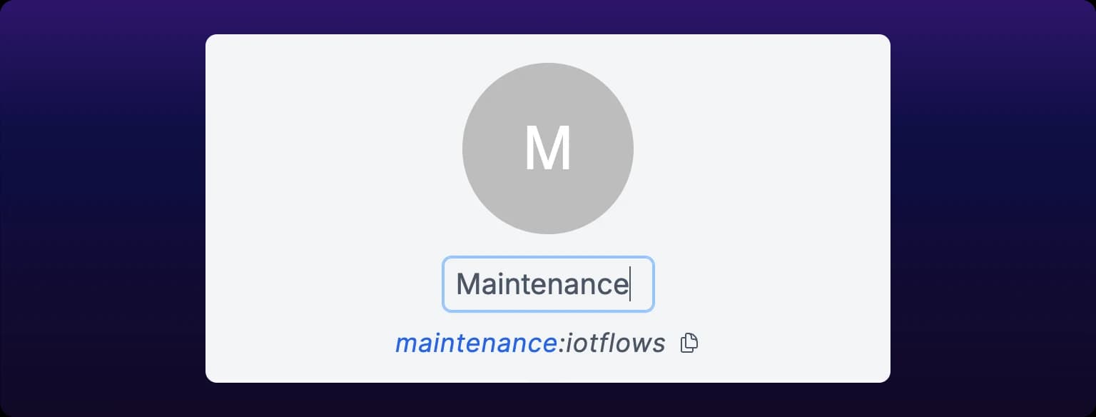The top of a team page. A large circular team avatar lettered M sits above the team name, open as an editable text field holding Maintenance with the cursor in it, and below that the handle reads maintenance:iotflows with a copy button to its right