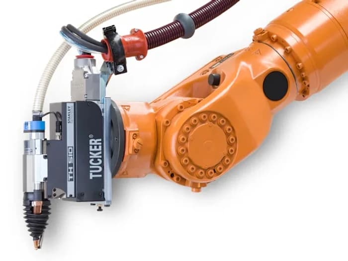 A Tucker TH510 stud-welding head mounted on the wrist of an orange industrial robot, its cable package curving over the arm.