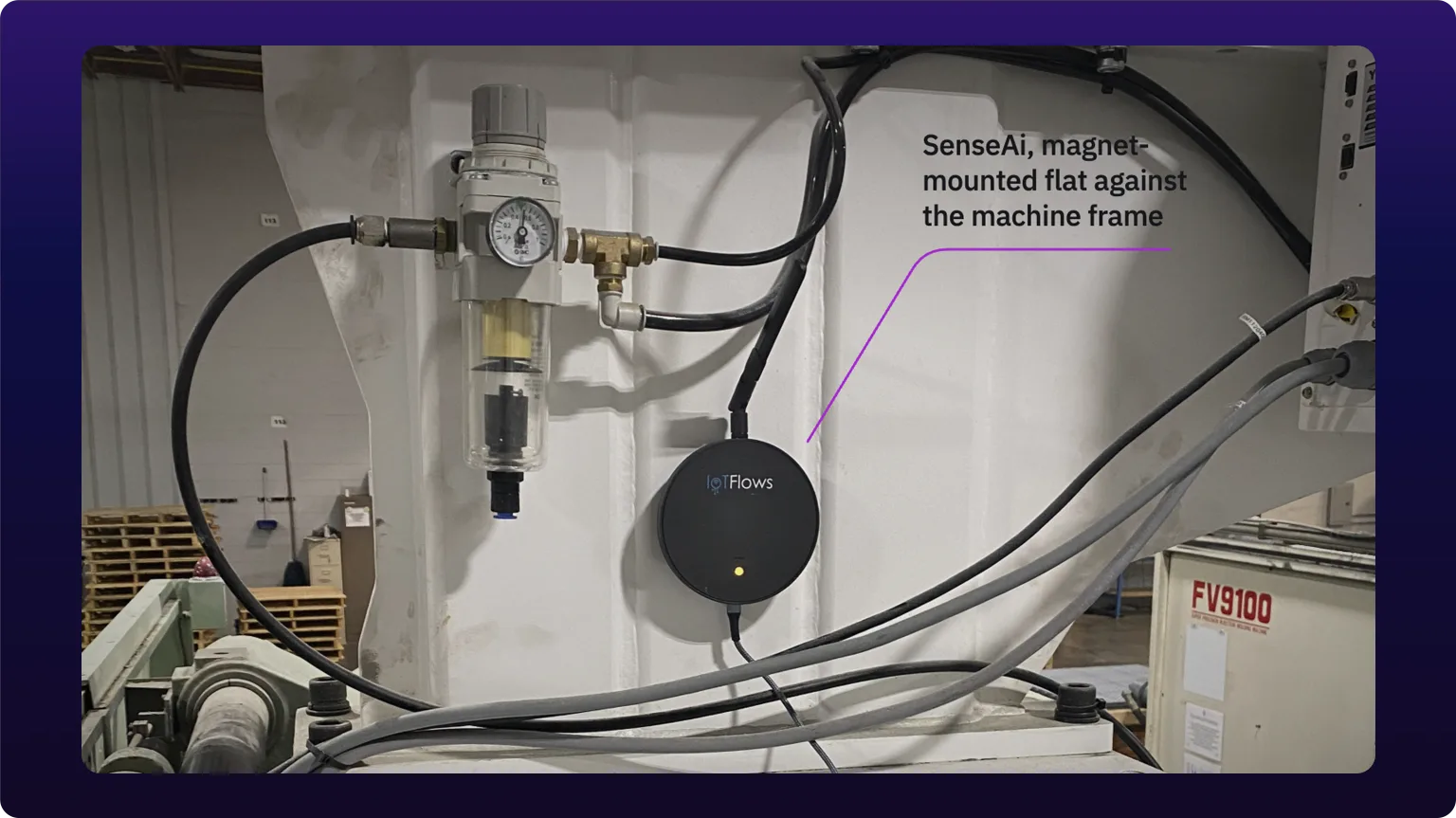 A SenseAi magnet-mounted on the white-painted frame of an injection molding machine, its USB cable running down to power, with a violet callout line labeling the sensor
